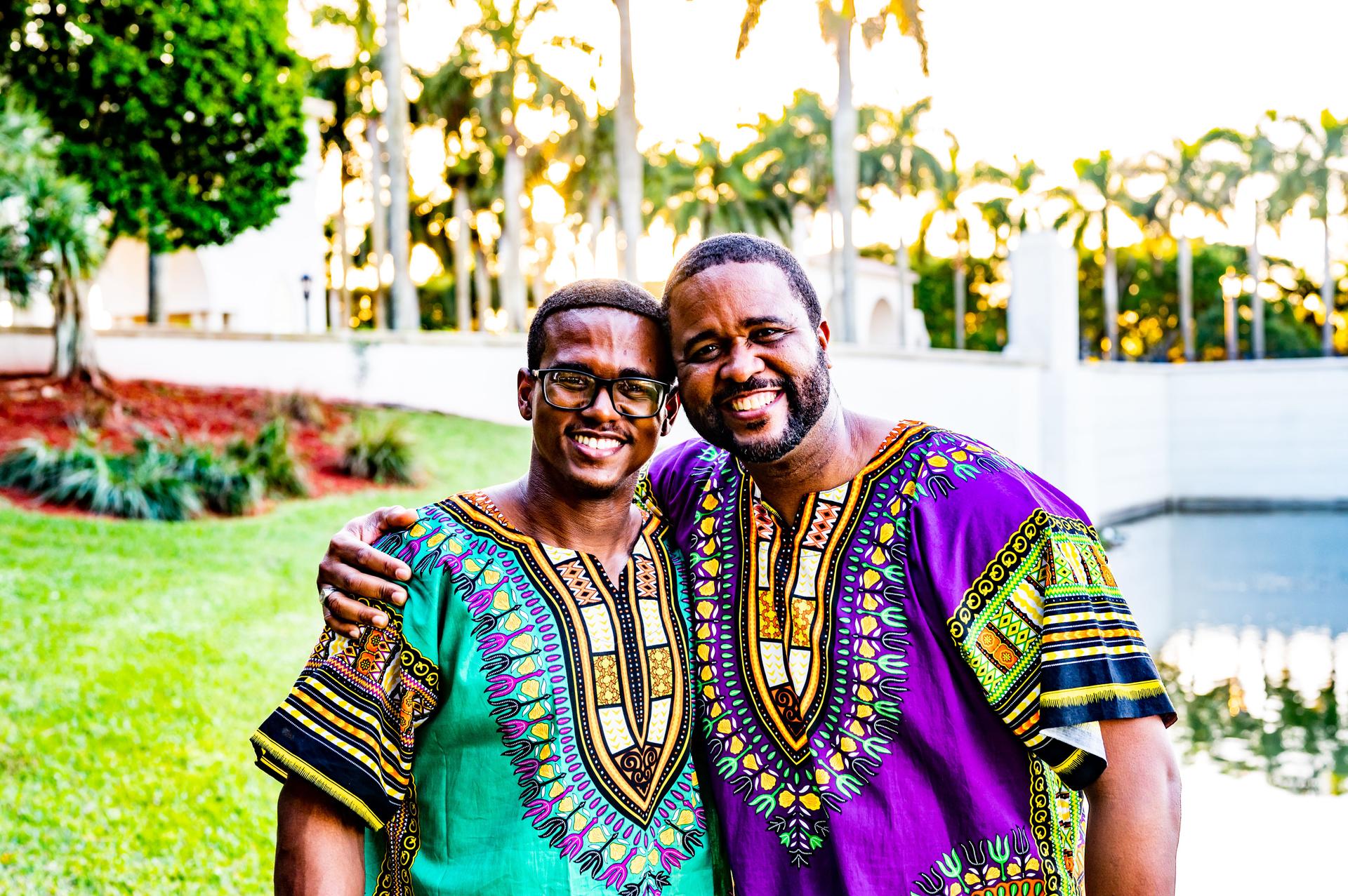 Two adult men dressed in dashikis traditional African clothing to celebrate Kwanzaa in happy posed outdoor photo
