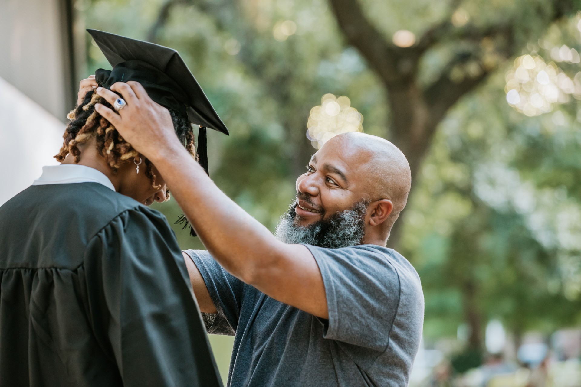 Helping his son with his mortarboard cap, a dad prepares him for graduation.